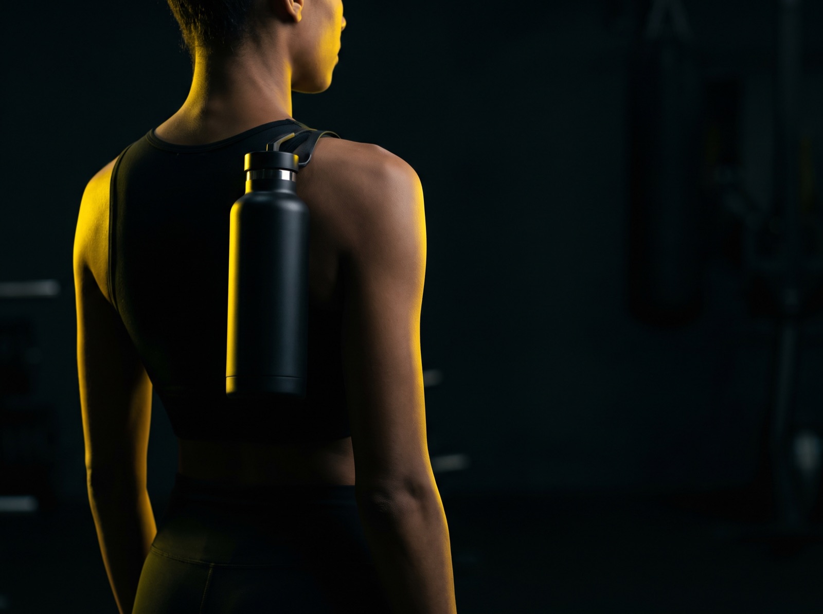 Athlete rim-lit in yellow resting a bottle on their shoulder