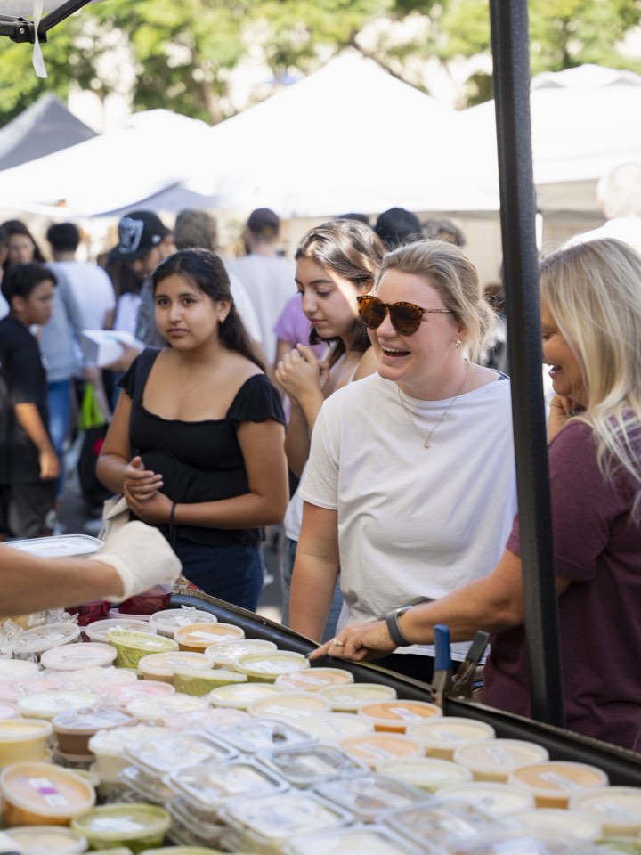 Shoppers moving between stalls at an outdoor market